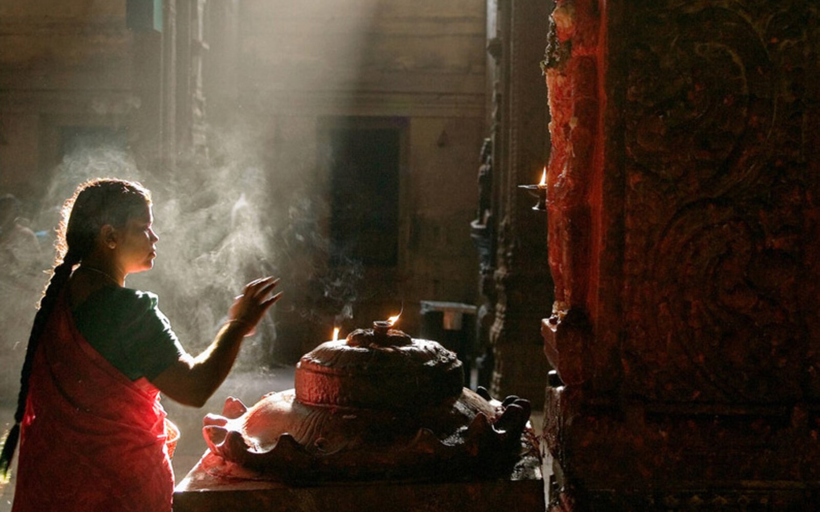 A devotee offering prayers before lamps at the Madurai Meenakshi temple